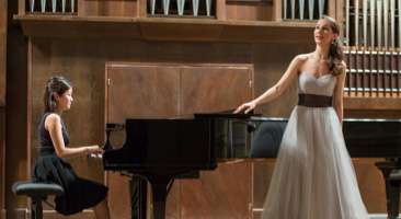 girl playing the piano with performer singing