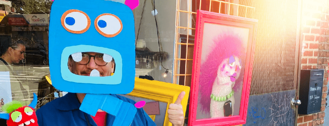 A smiling man standing in an outdoor marketing with sock puppets surrounding him