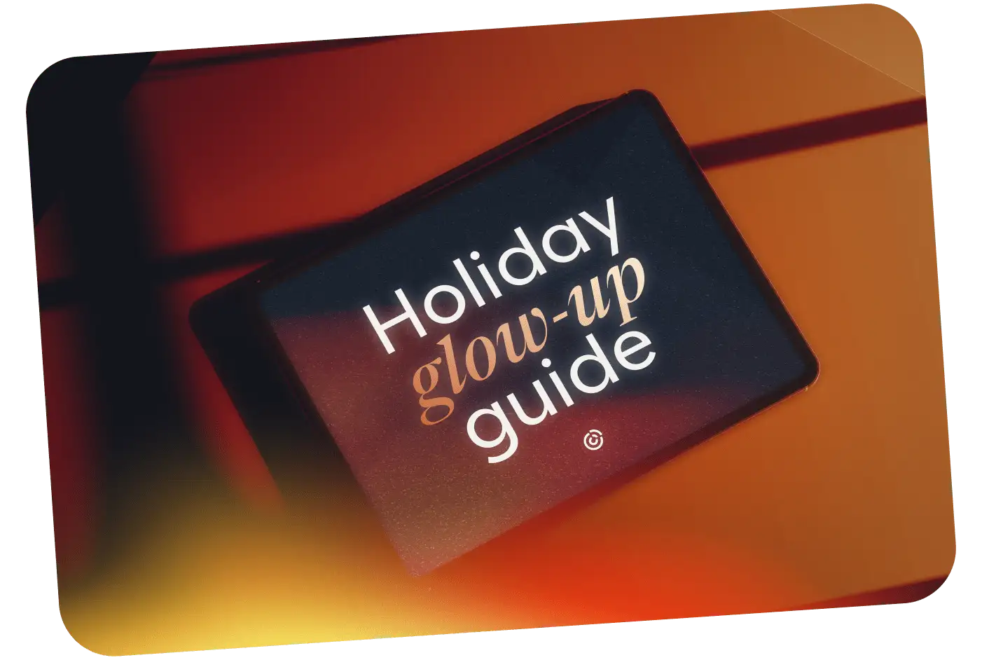 Tablet displaying "Holiday glow-up guide" text on a dark screen against a warm orange-red background.