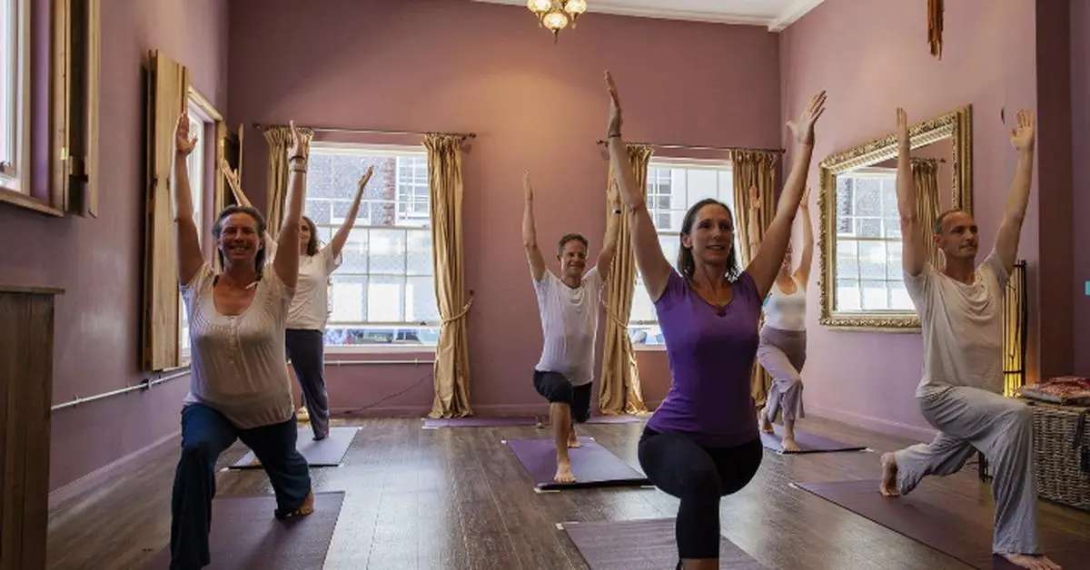 People in warrior 1 yoga pose in studio