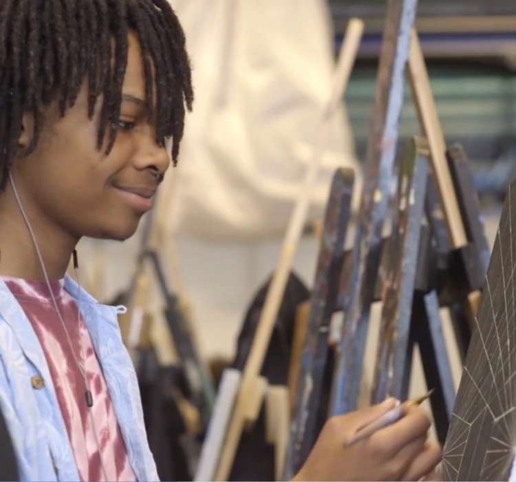 Teenager paints with paintbrush at Artists for Humanity.