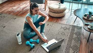 woman working out on the floor next to her computer