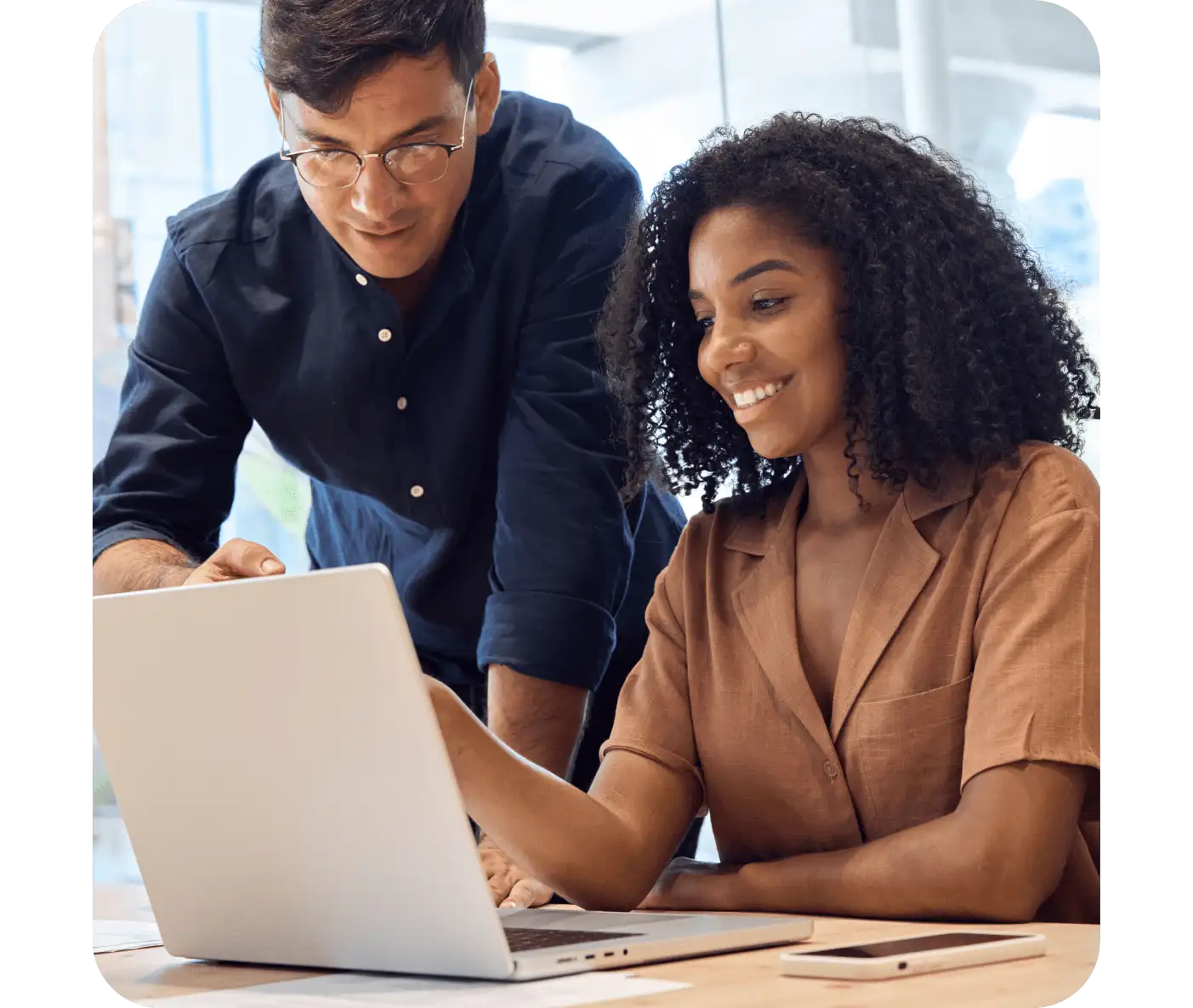A woman looking at a laptop and a man standing next to her pointing to the laptop screen