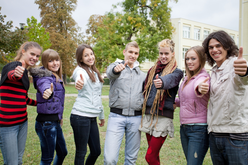 Group of happy teenagers near high school building.