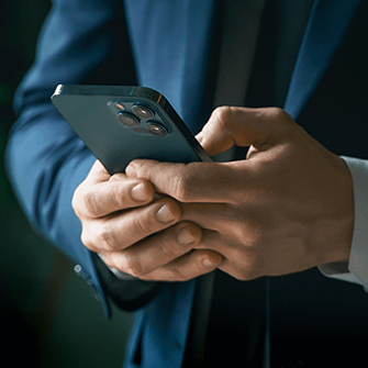 A person wearing a suit holds a smartphone.