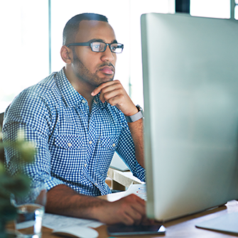 A man looking closely at his monitor screen