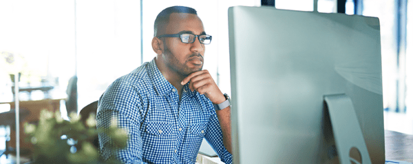 A man looking closely at his monitor screen