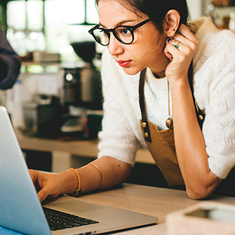 This is an image of a woman looking at her laptop.