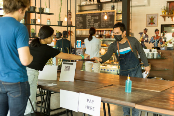 Social distancesmall business waiter serving customer in cafe