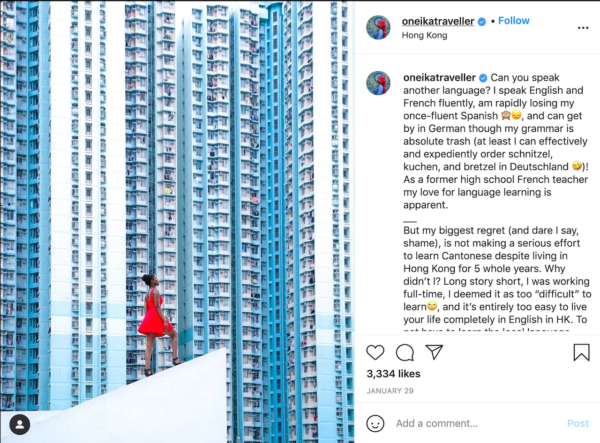 Best Travel Instagrams - Oneika Raymond's post featuring her ina bright red dress with a background of blue sky-scraper-esque apartment buildings
