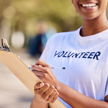 A person wearing a "Volunteer" t-shirt holds a clipboard.