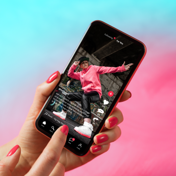 A hand holding a phone displaying a TikTok video.
