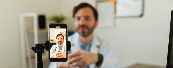 A man films himself with a smartphone on a tripod.