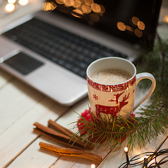A holiday mug sits in front of a laptop.