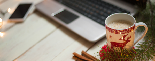 A holiday mug sits in front of a laptop.