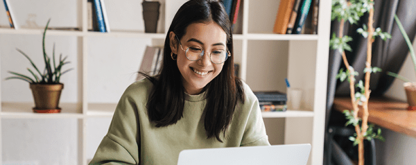 A woman smiling while working on her laptop in a home office