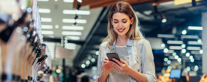 Woman looking at phone in grocery store