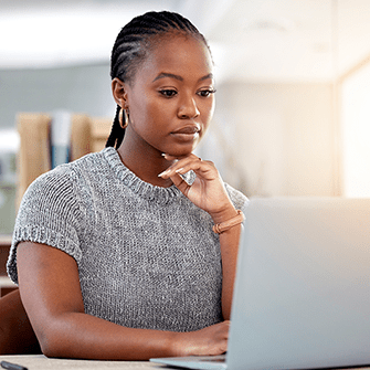 A woman sits in front of a laptop looking at the screen.