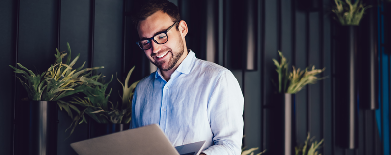 automated email follow-up marketing professional on laptop n front of plant wall
