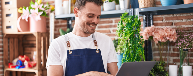 Welcome email examples blog header Male flower shop owner working on a welcome email