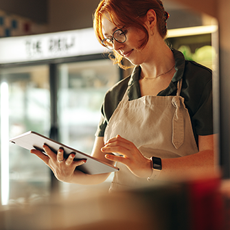 A woman in an apron looks down at a tablet.