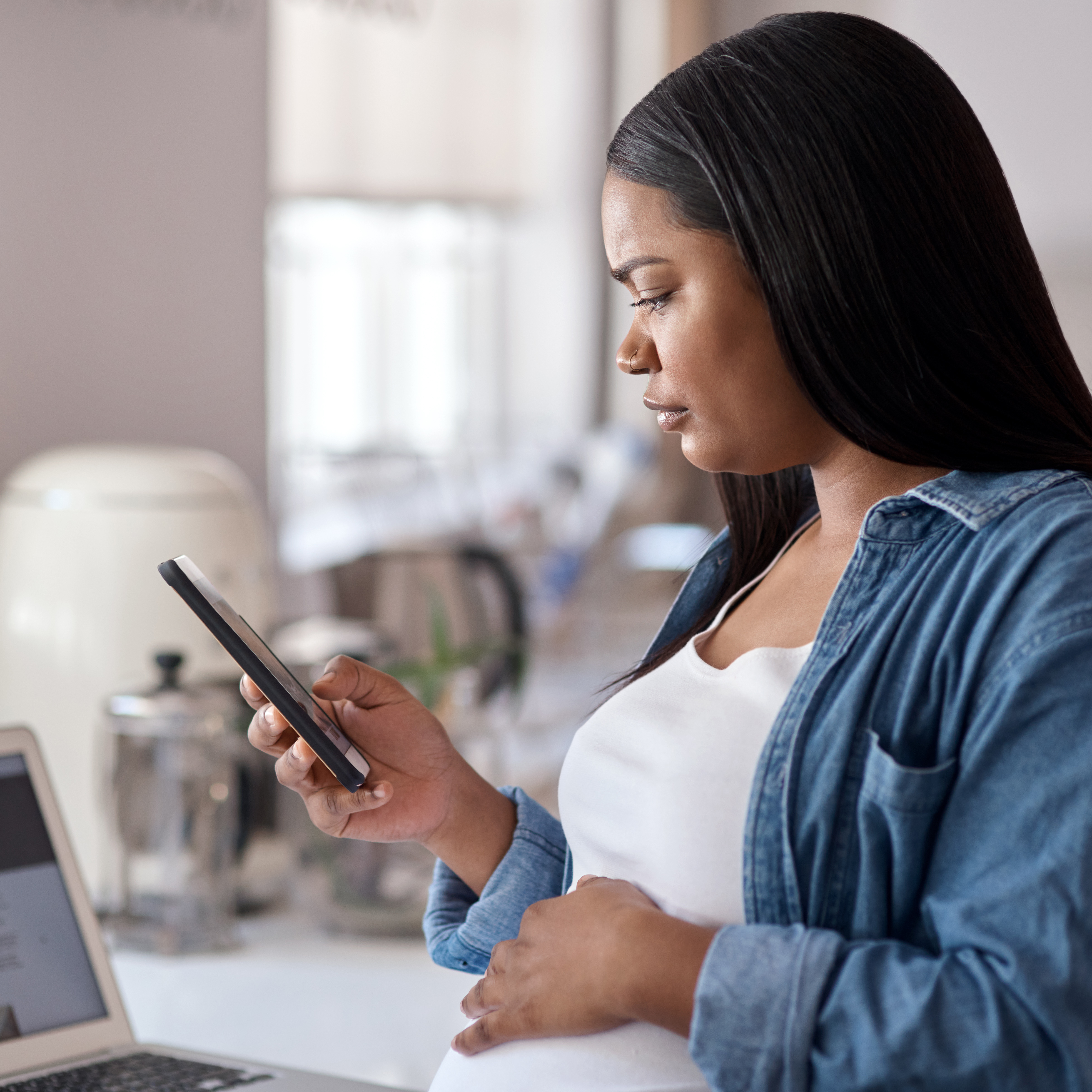 A pregnant woman looks at her smartphone screen.