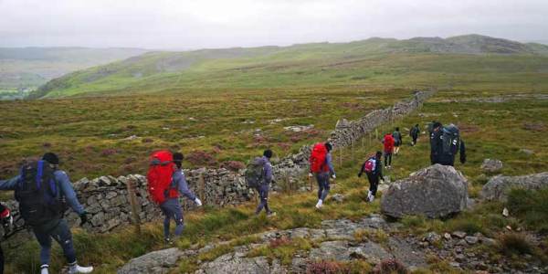 A group of soccer players in outdoor gear hiking through the Welsh hills as part of an outdoor leadership experience.