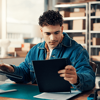 A person sits at a desk holding a tablet.