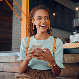 A woman sits on a bench holding a smartphone.