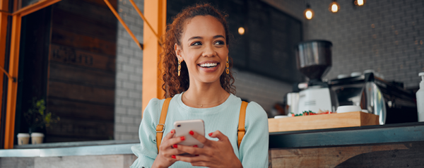 A woman sits on a bench holding a smartphone.