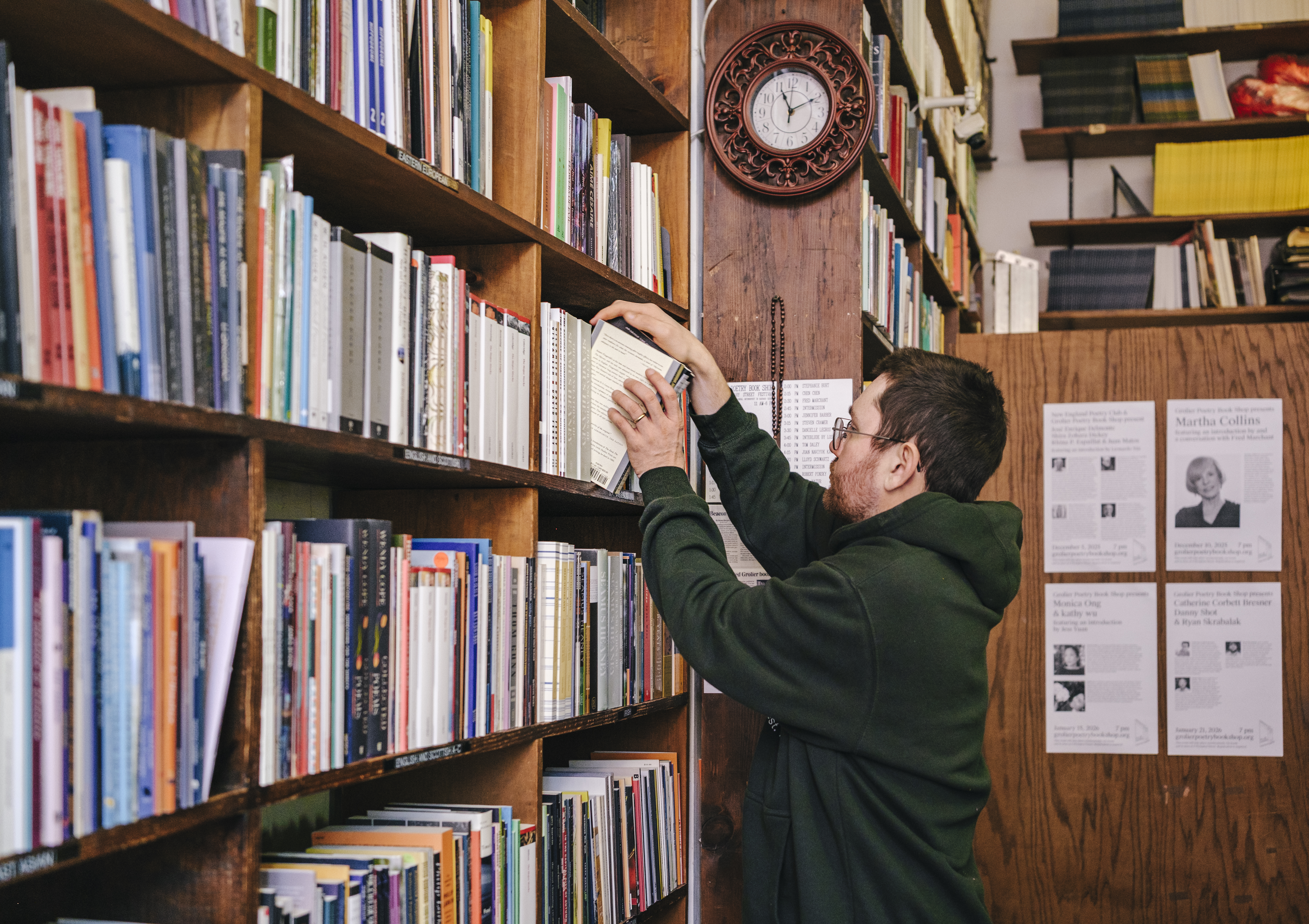 A man places books on a bookshelf.