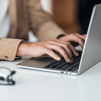 Hands type on a laptop keyboard.
