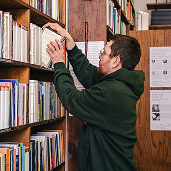 A man shelves books on a bookshelf.