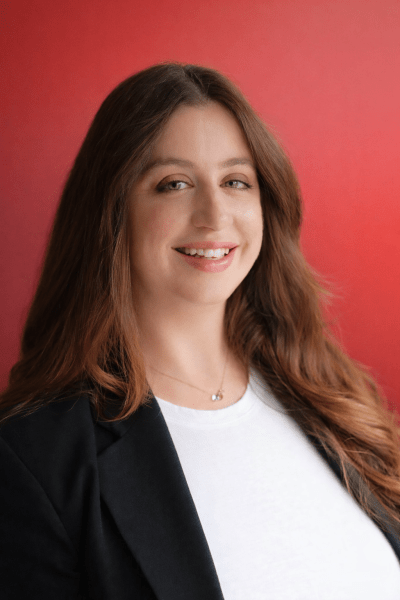Photograph depicts Marketing Manager Clair Brewster-Kerby, a young woman with brown against a red background.