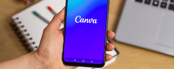 A person holds a smartphone displaying the Canva logo.