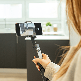 A person films an empty kitchen with a smartphone.