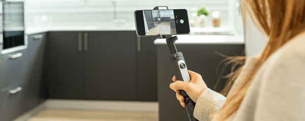 A person films an empty kitchen with a smartphone.
