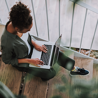 A woman sitting with her laptop placed on her lap