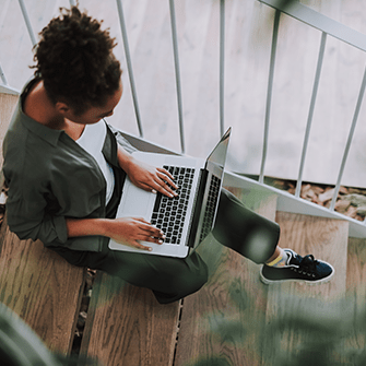 A woman sitting with her laptop placed on her lap