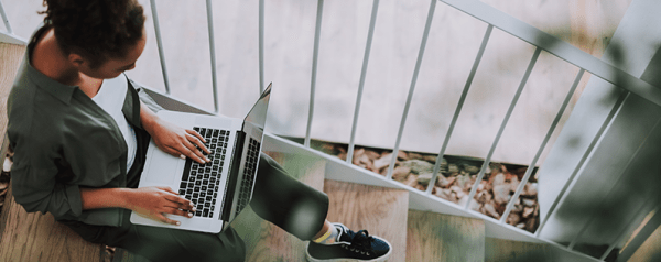 A woman sitting with her laptop placed on her lap