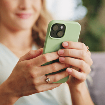 A person holds a smartphone in a light green case in both hands.