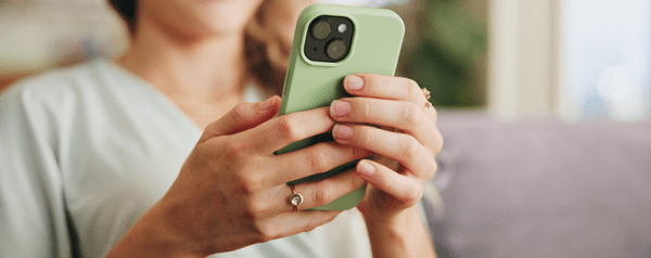 A person holds a smartphone in a light green case in both hands.