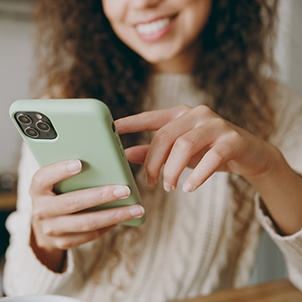 A smiling woman holds a smartphone.