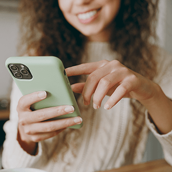 A smiling woman holds a smartphone.