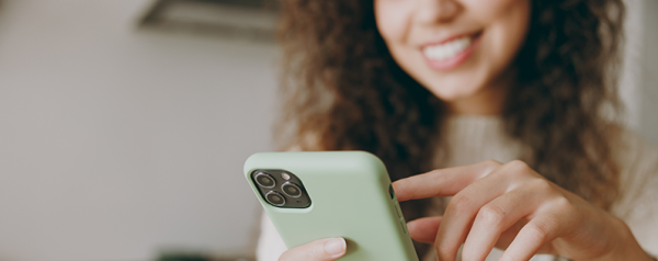 A smiling woman holds a smartphone.
