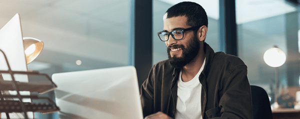 A man smiling in front of his laptop