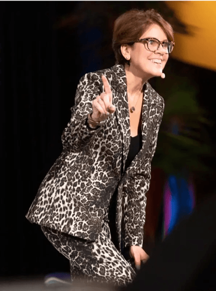 Top marketing specialist Ann Handley smiling and wearing a leopard suit, probably presenting at a conference.