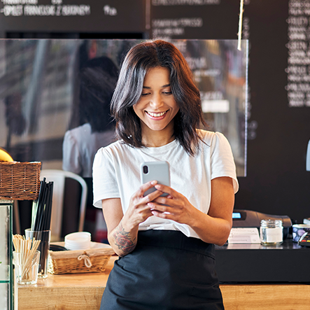 This is an image of a woman smiling while looking at her cell phone