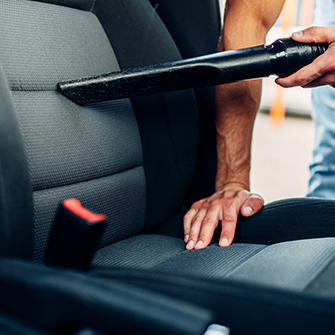 A person vacuums the front seat of a car.