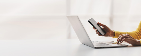 A person with a laptop, holding a mobile phone